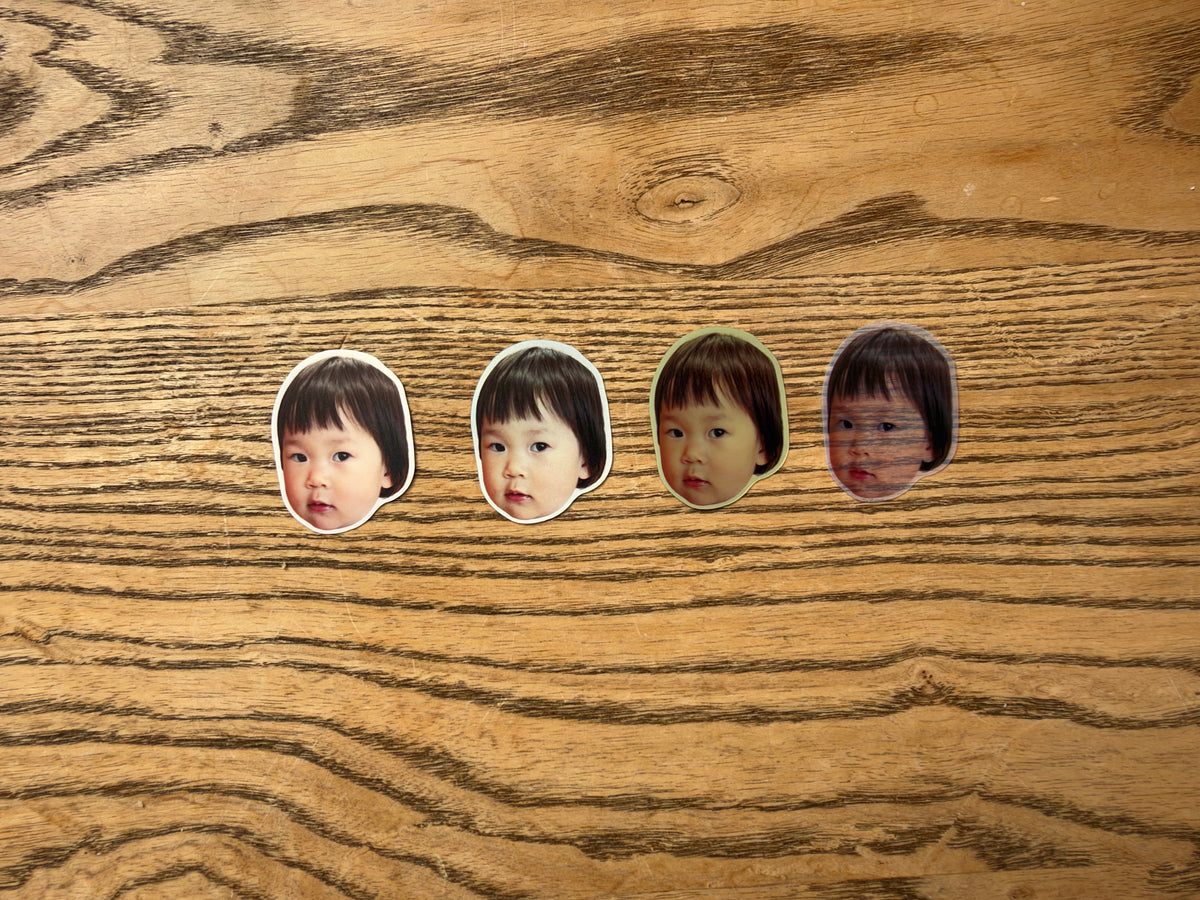 Four portrait sticker samples photographed together on wood