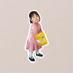 A single full-body cutout sticker of a toddler in a pink dress and black shoes, cut with a white border