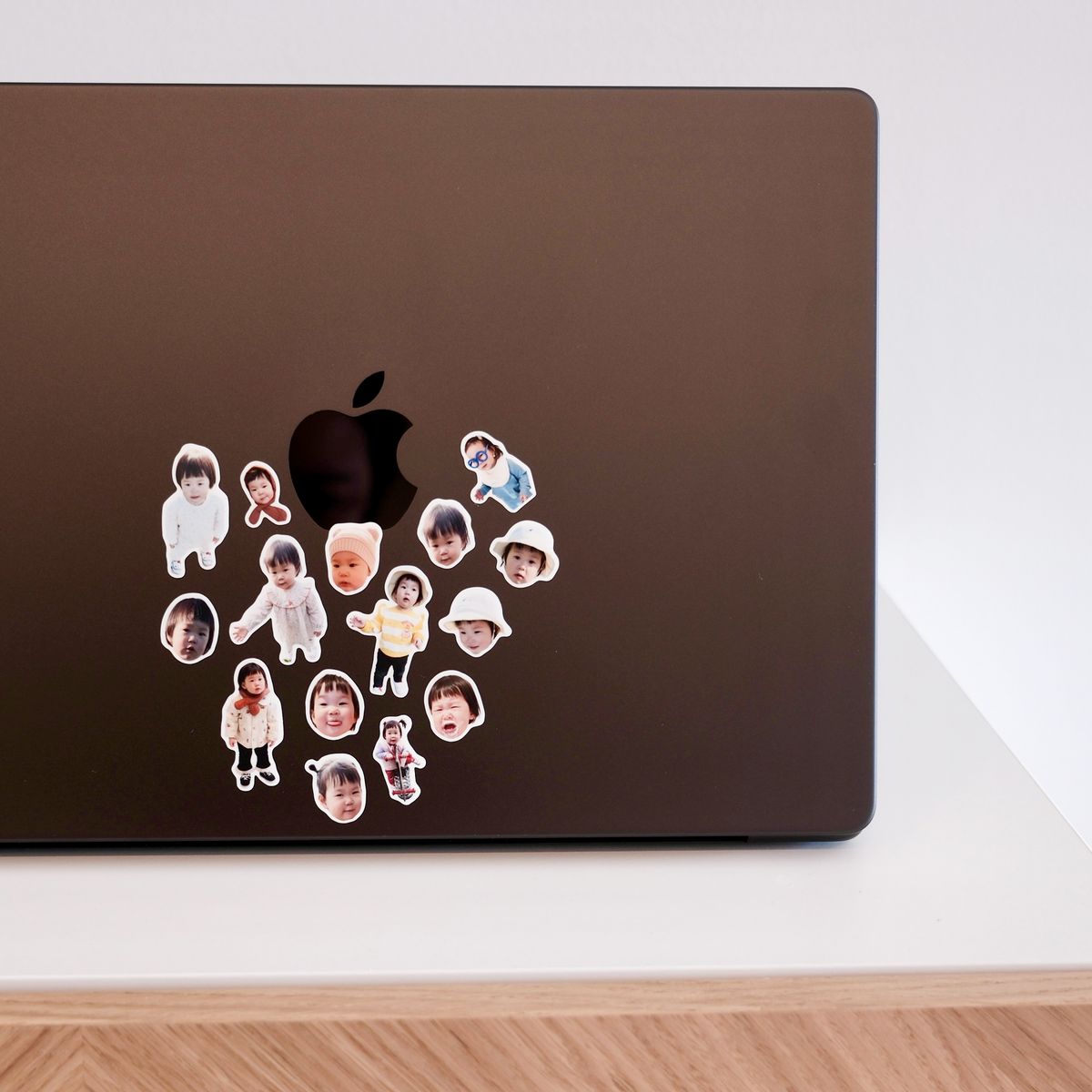 A cluster of small face stickers gathered around the Apple logo on a bronze MacBook lid