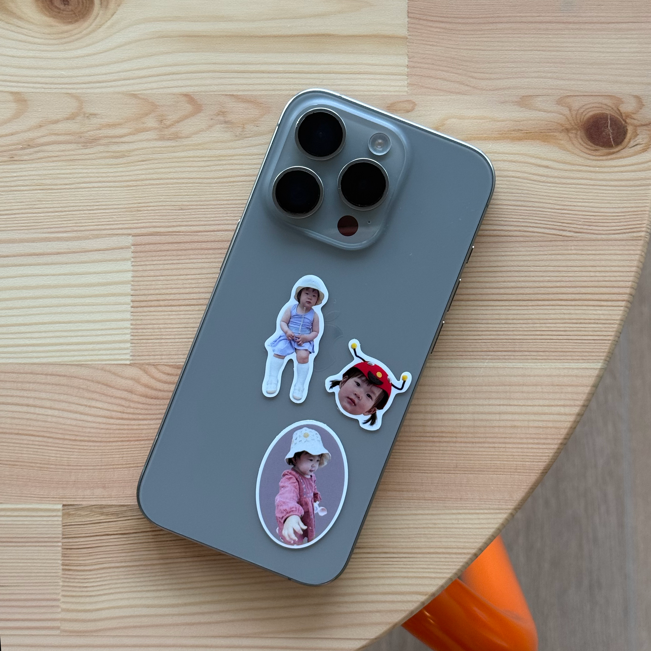 Three Package Mini stickers on the back of a grey iPhone resting on a light wood table