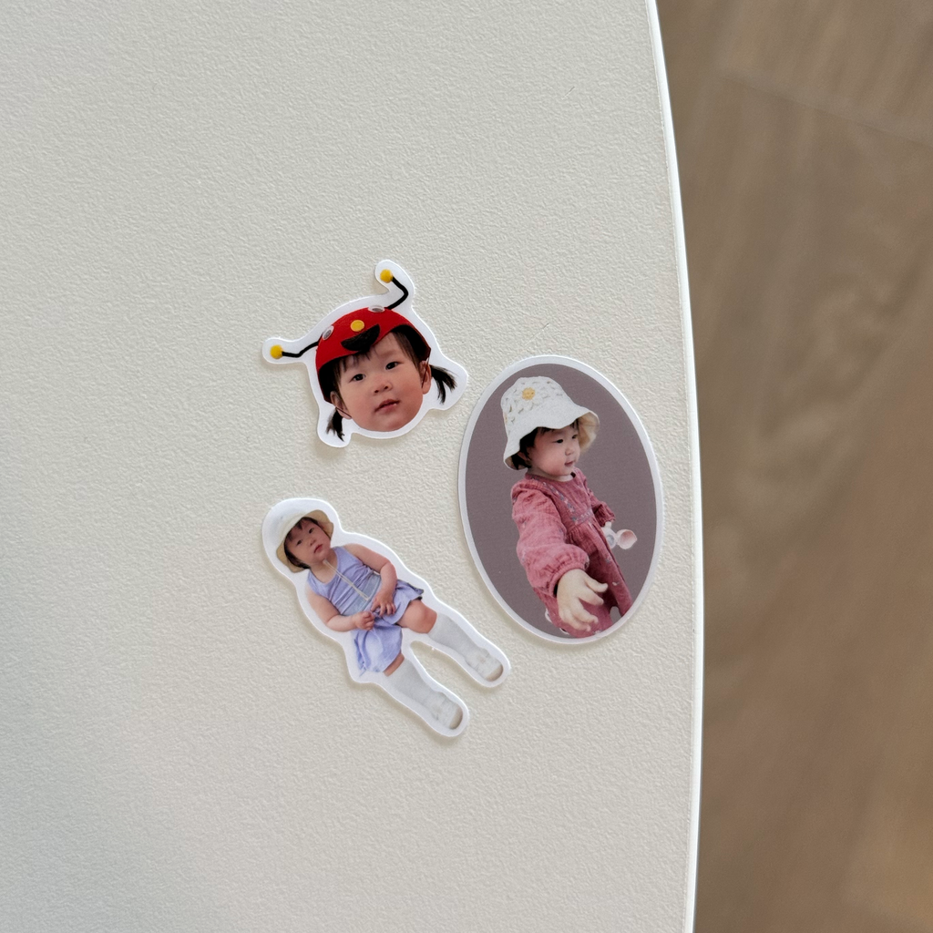 Three Package Mini stickers on a white tabletop: a ladybird-hat face, a full-body cutout and an oval portrait