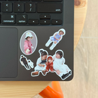 Five Package Mini stickers on the palm rest of a black laptop, mixing oval portraits with full-body cutouts